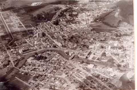 Vista aérea de Itajubá cortada pelo rio Sapucaí em duas metades pela ponte de Arcos junto à fábrica de doces Vera Cruz